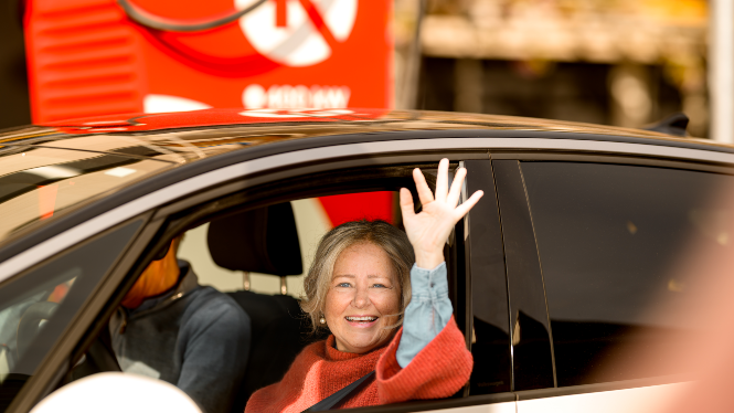 billede af kvinde i bil, der er færdig med at lade og vinker tilfreds