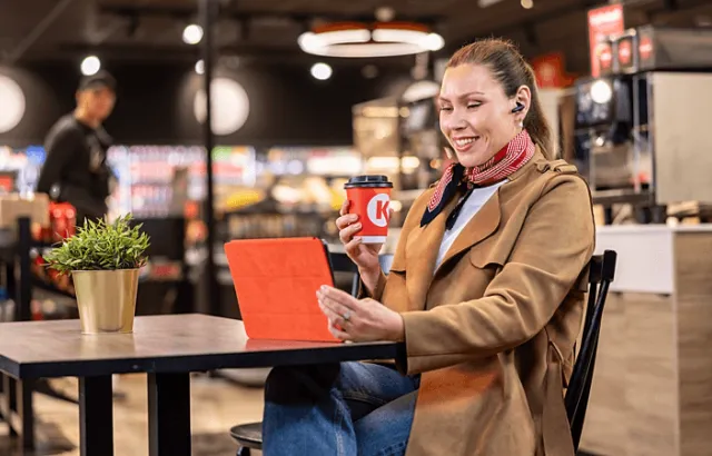 bilde av smilende dame med kaffekopp på stasjon 