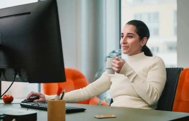 Woman working at her desk, while holding her mug